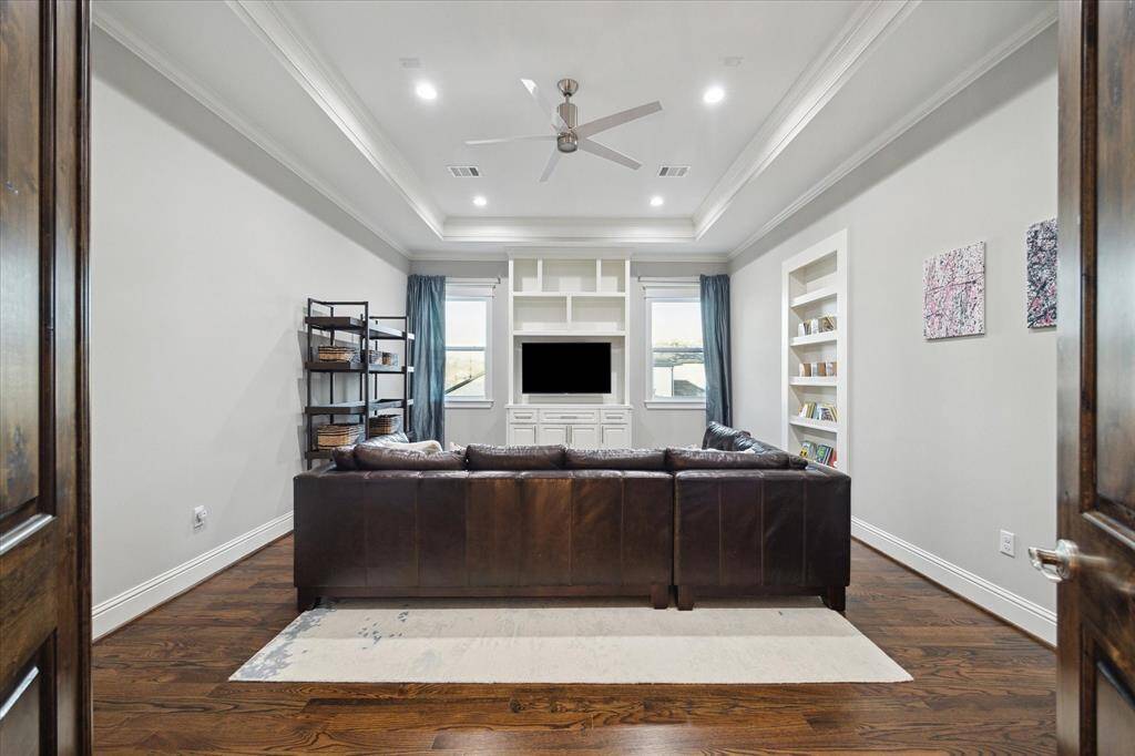 The second floor offers a fabulous game room with built-in media cabinet, tray ceiling, hardwood floors, designer ceiling fan, recessed lighting, and crown molding.
