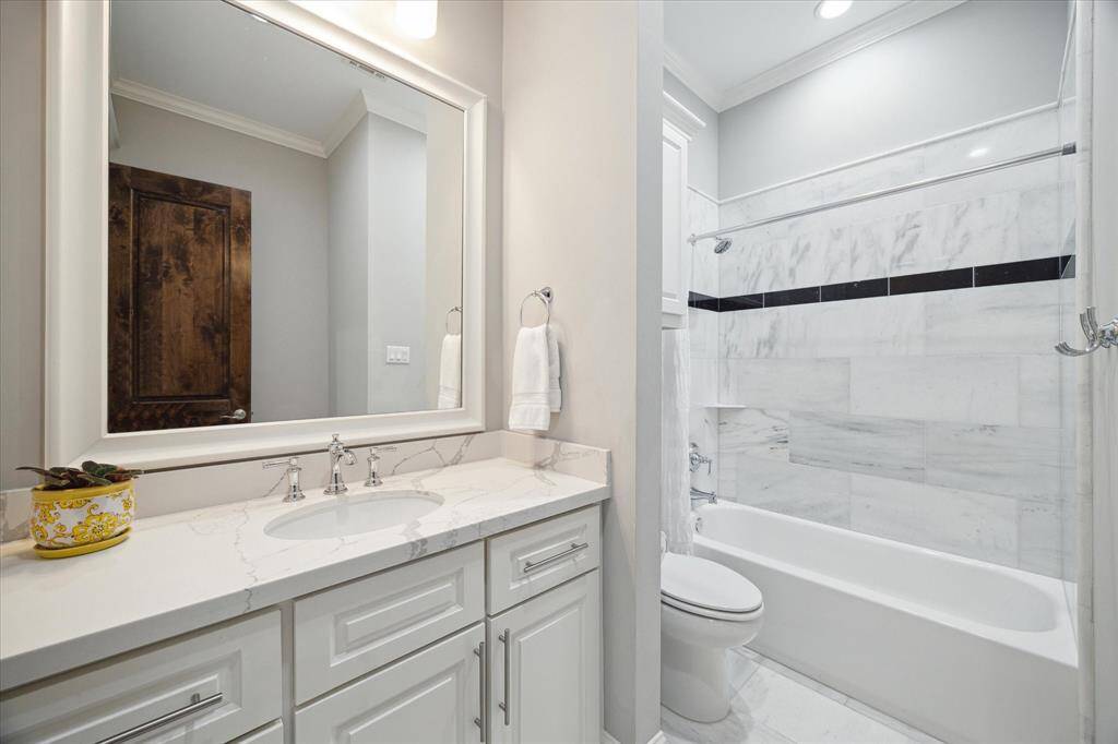 This is the ensuite bath for guest bedroom 2 which includes a spacious vanity, quartz counters, tub/shower combo with natural stone surround, and natural stone tile floors.