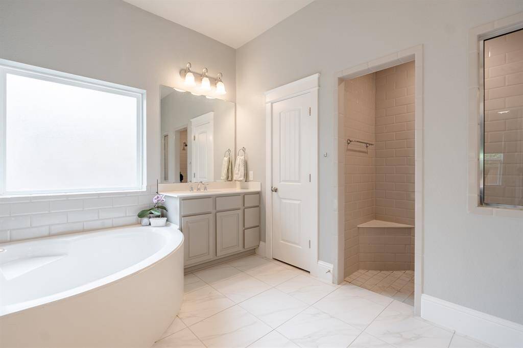 Spa-inspired primary bathroom featuring an extended walk-in shower, oversized soaking tub, and dual vanities