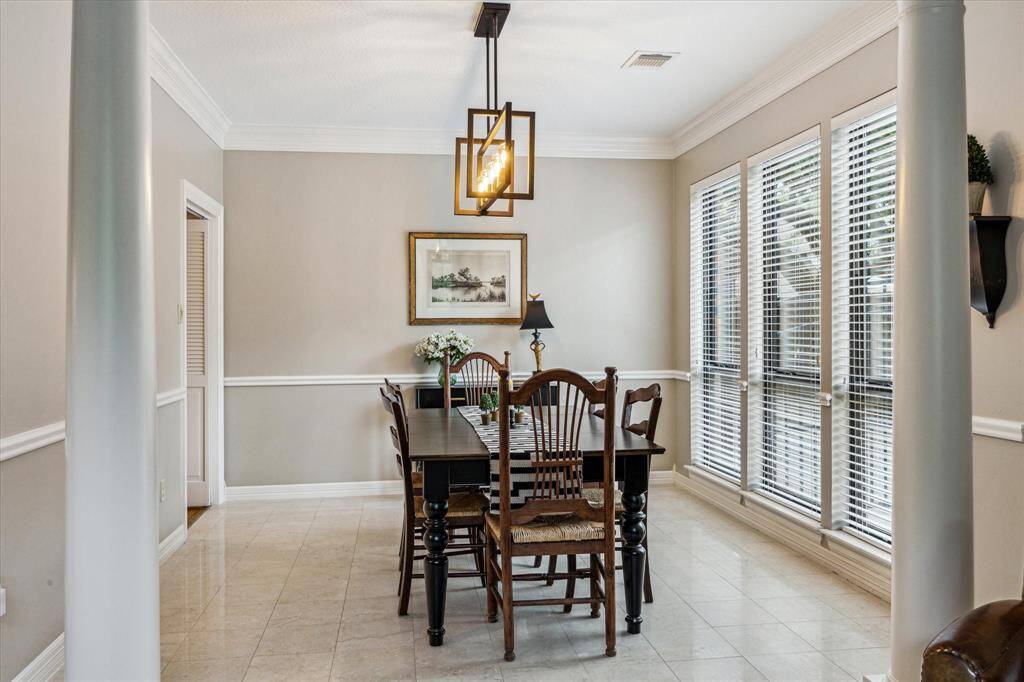 The dining room features a timeless design with elegant moldings, a wall of windows, and an updated light fixture.