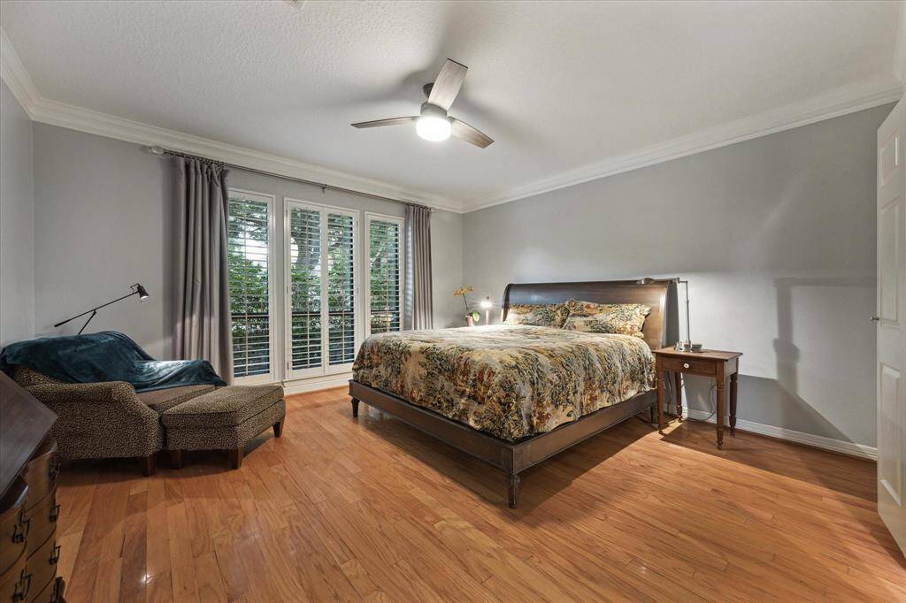 The primary bedroom offers a soft, neutral color palette, plantation shutters, and hardwood flooring.