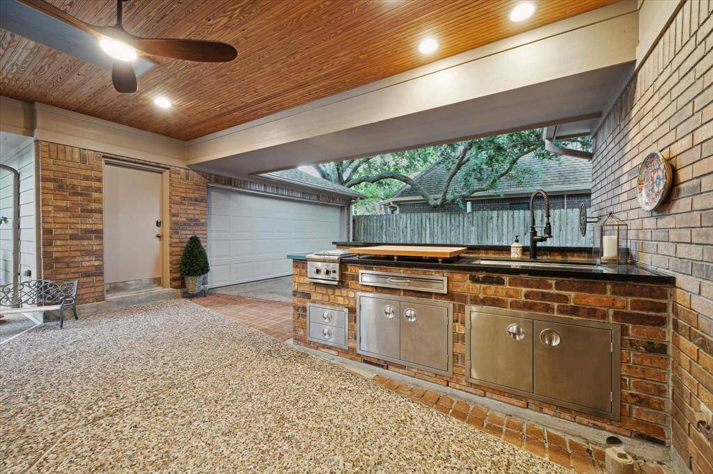 Step outside to this architecturally designed covered patio. It offers an outdoor kitchen and serving bar. It is open to the gated section of the driveway on one side, and to an outdoor living area and pool on the other side.