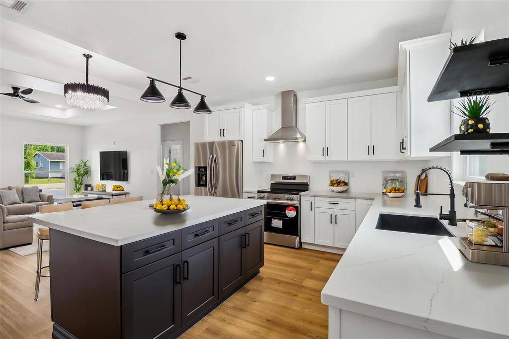 It boasts sleek white cabinetry paired with a contrasting dark island. Stainless steel appliances including a range hood, offers style and functionality.