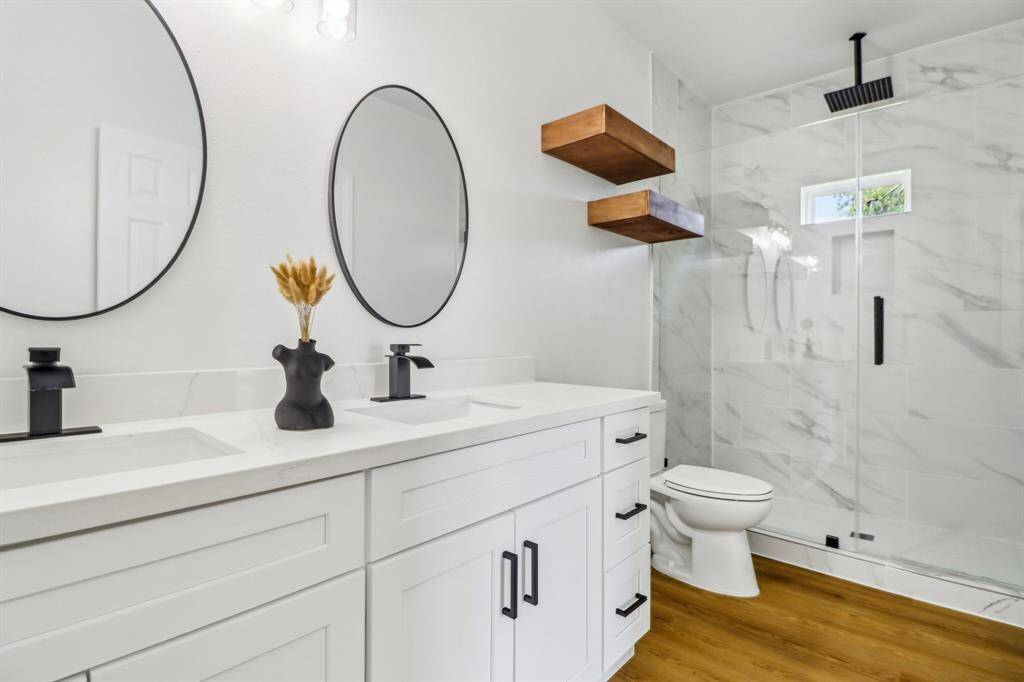 Step into the bathroom with beautiful and spacious countertops, two vanity mirrors with stainless steel appliances that give a gorgeous contrast against the marble shower wall and the crisp, white cabinetry.