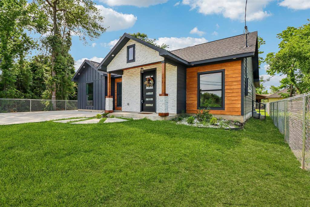 The striking exterior boasts a sophisticated blend of dark siding, natural wood accents, and crisp white stone.