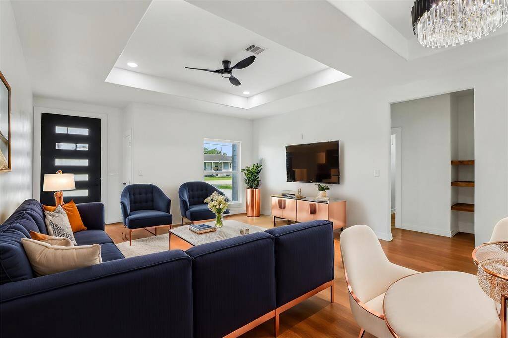 The soaring tray ceiling, adorned with a contemporary ceiling fan and recessed lighting, creates an open and airy ambiance.