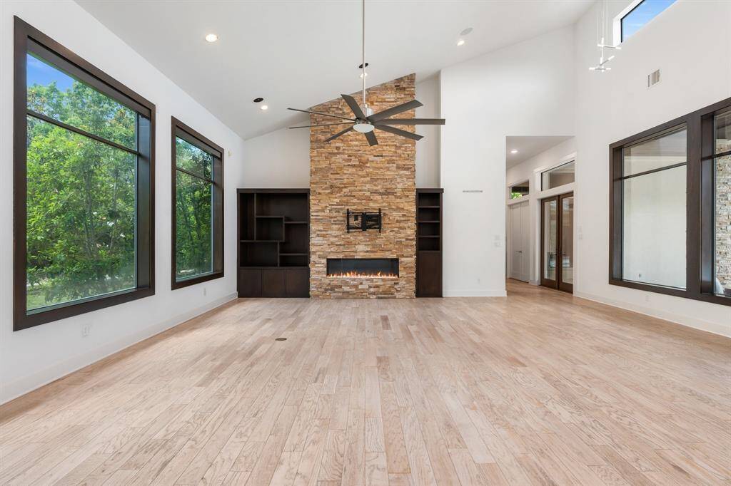 High angled ceilings, wood flooring, natural light from all sides as well as high transoms above create a casual atmosphere in this spectacular home. The Primary Suite is down the hall beyond the glass French doors, as well as another bedroom suite and guest powder room.