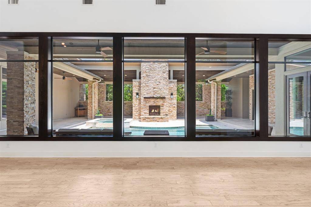 The Great room has two walls of glass, one overlooking the courtyard pool area, the other viewing the inviting back yard adorned with dozens of magnolia and crepe myrtle trees.