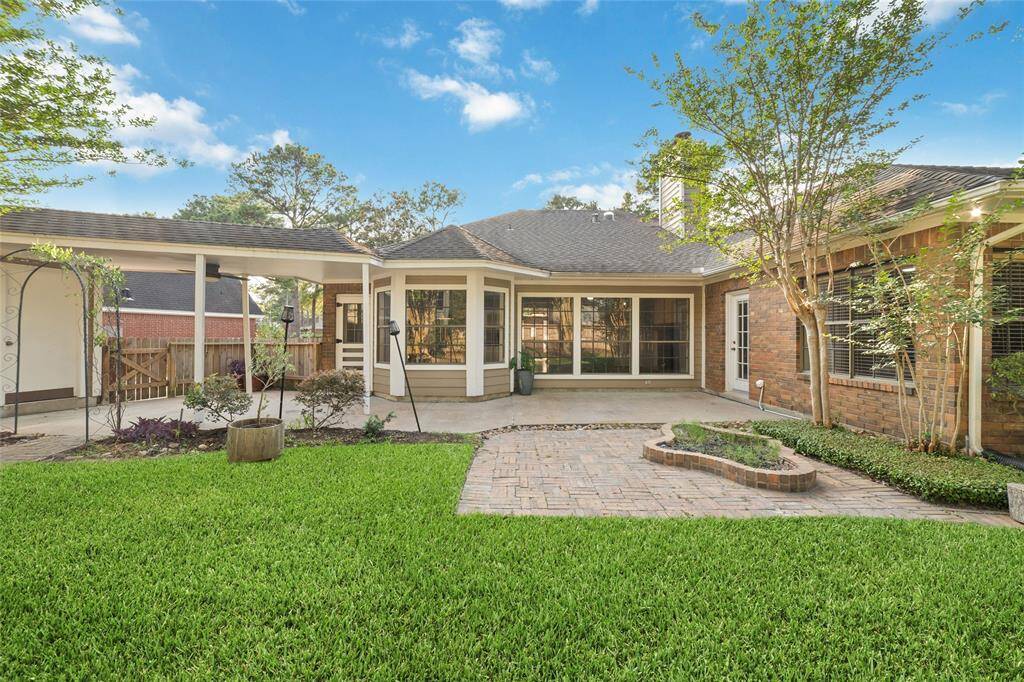 Charming backyard with lush green lawn, a spacious patio, and a cozy brick facade. Ideal for outdoor entertaining and relaxation.