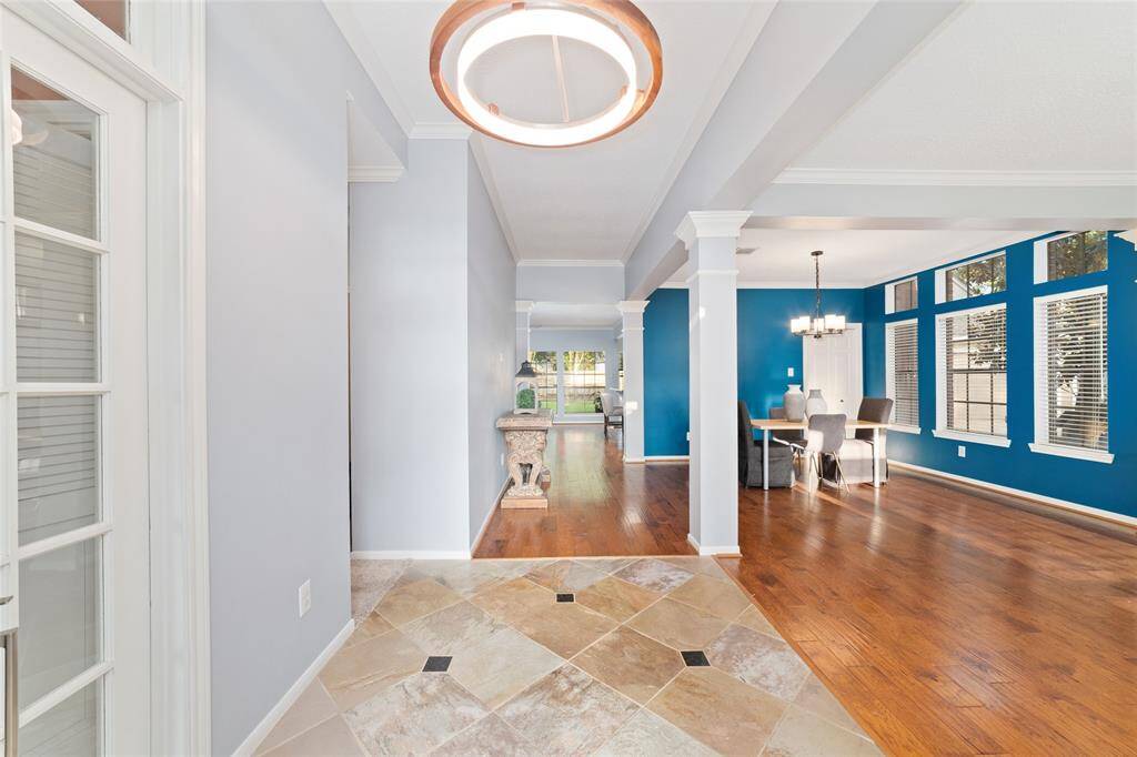 This home features a bright, open entrance with elegant tile flooring that transitions to rich hardwood. The dining area is highlighted by large windows and a stylish light fixture, offering a welcoming and modern space.