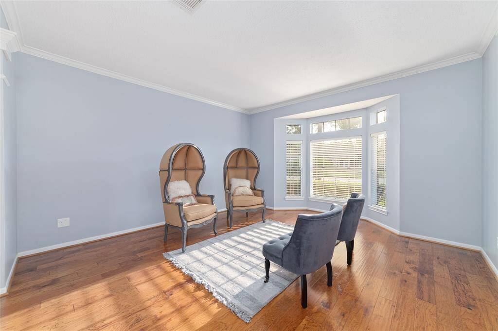 Bright and inviting room with large windows, light blue walls, and hardwood floors. Features elegant seating and a cozy atmosphere perfect for relaxation.