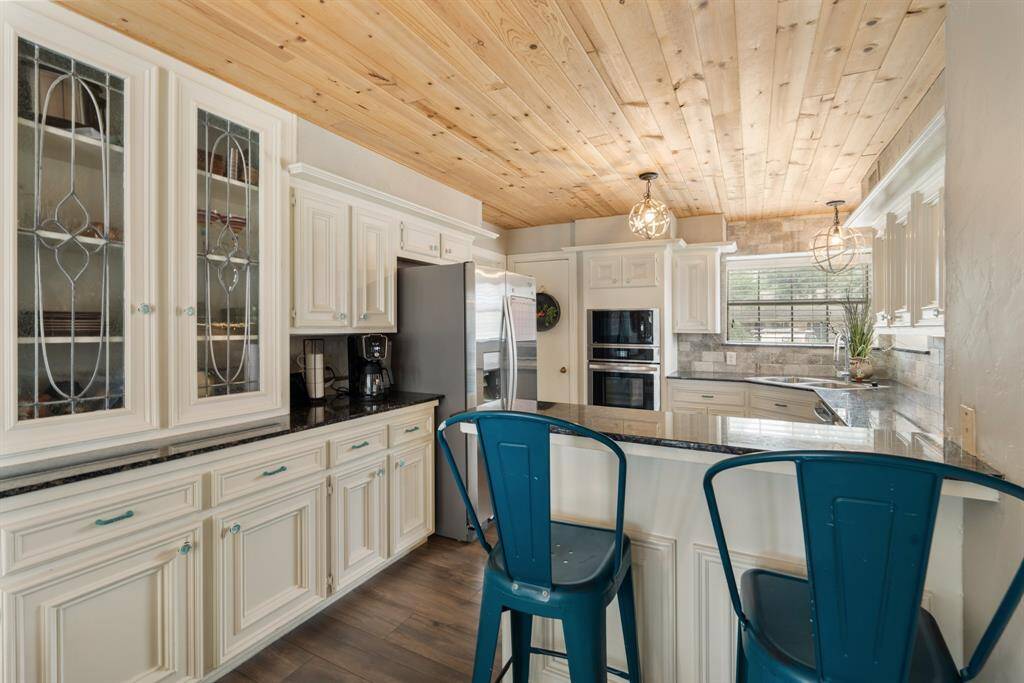 The heart of the home! This stunning chef’s kitchen features an upgraded accent ceiling, white cabinetry, granite countertops, sleek stainless steel appliances, and stylish lighting—perfect for gathering and entertaining.