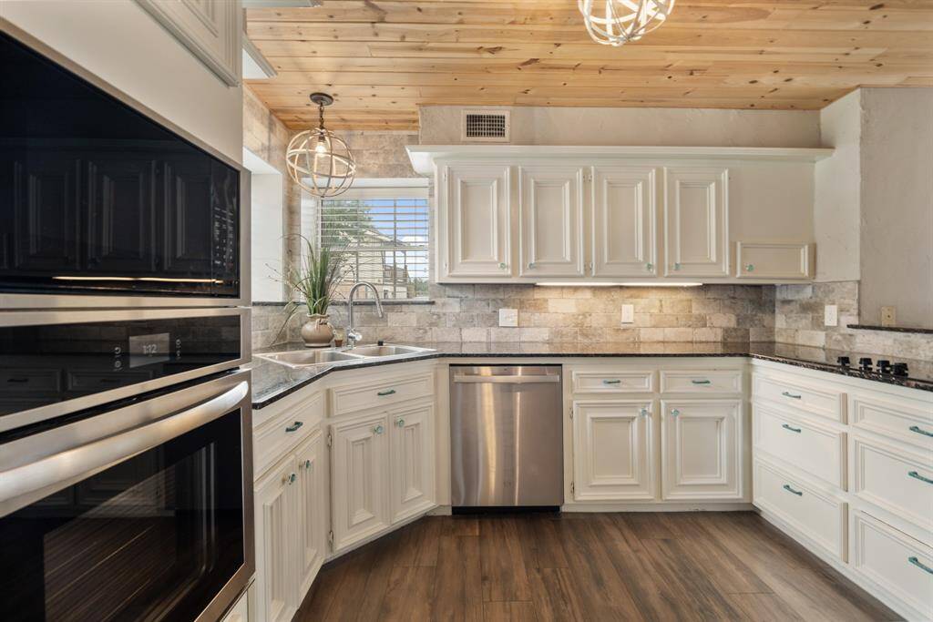 This stunning kitchen displays such a beautiful contrast with the light cabinets, neutral paint, dark granite countertops, light modern backsplash, and SS appliances!