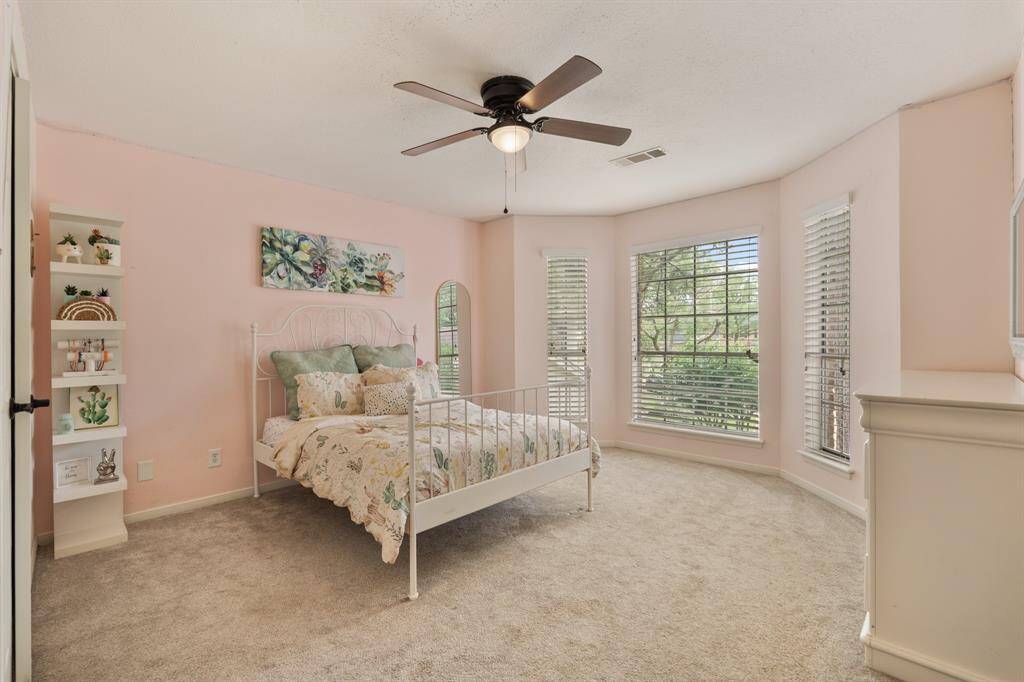 The final secondary bedroom is complete with a bay window, letting in bright naturl light, and it features plush carpet, a ceiling fan, a spacious closet, and fresh paint.