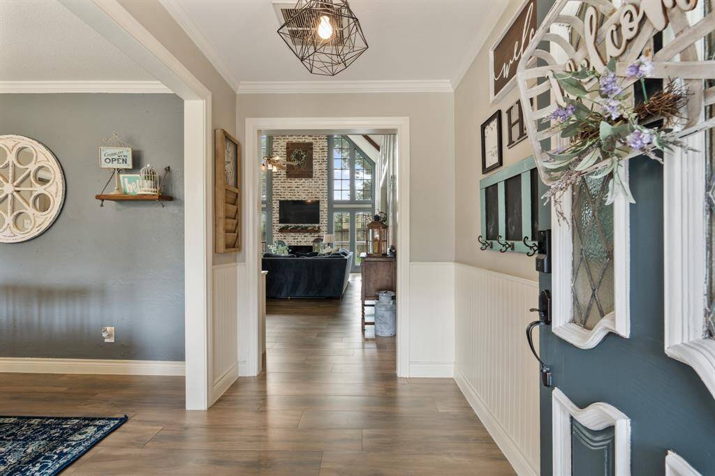 Walking in, you find a bright entryway with beautiful wood look tile flooring that continues throughout the first floor in the main living areas making it easy to clean and maintain. The entryway is complete with wainscoting, netural paint, crown molding, and modern light fixture.