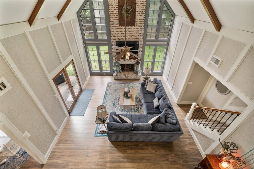 Soaring ceilings, abundant natural light, and a cozy brick fireplace create the perfect blend of charm and comfort in this stunning living room.