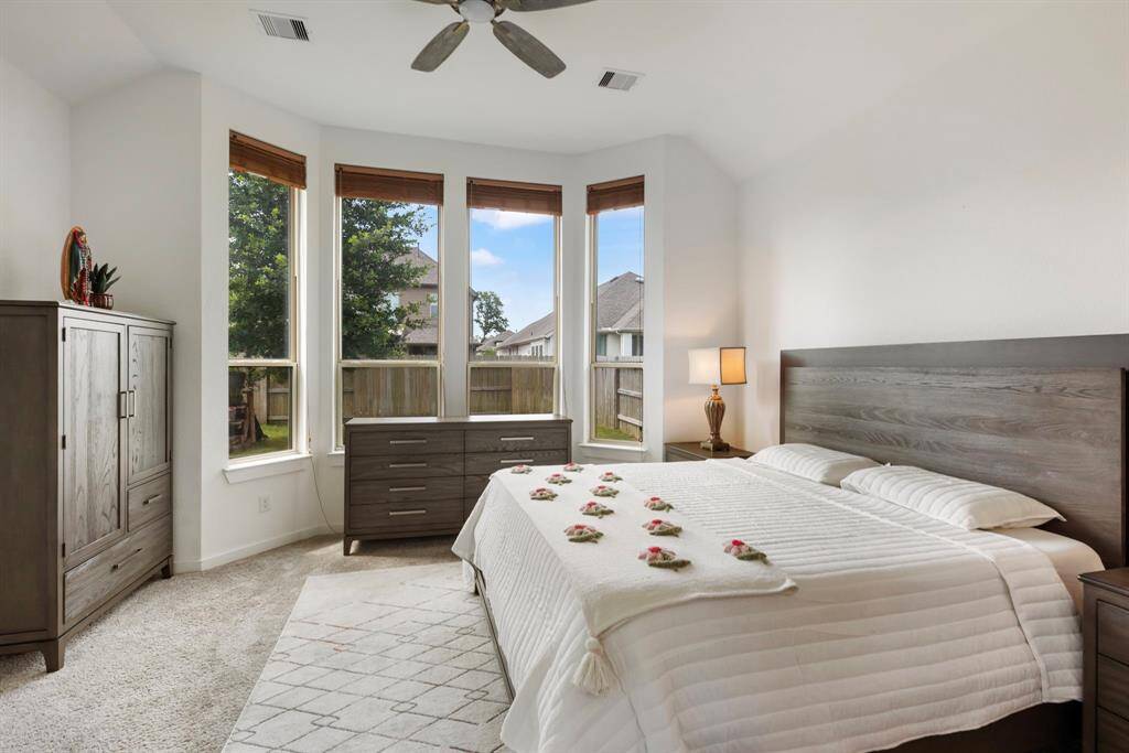 The primary suite combines comfort with style featuring soaring ceilings, sleek fan and neutral carpet and paint.