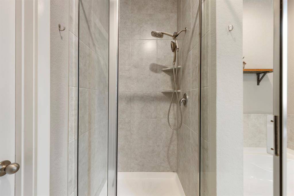 The separate walk-in shower is equipped with rain showerhead, tile surround and glass enclosure.