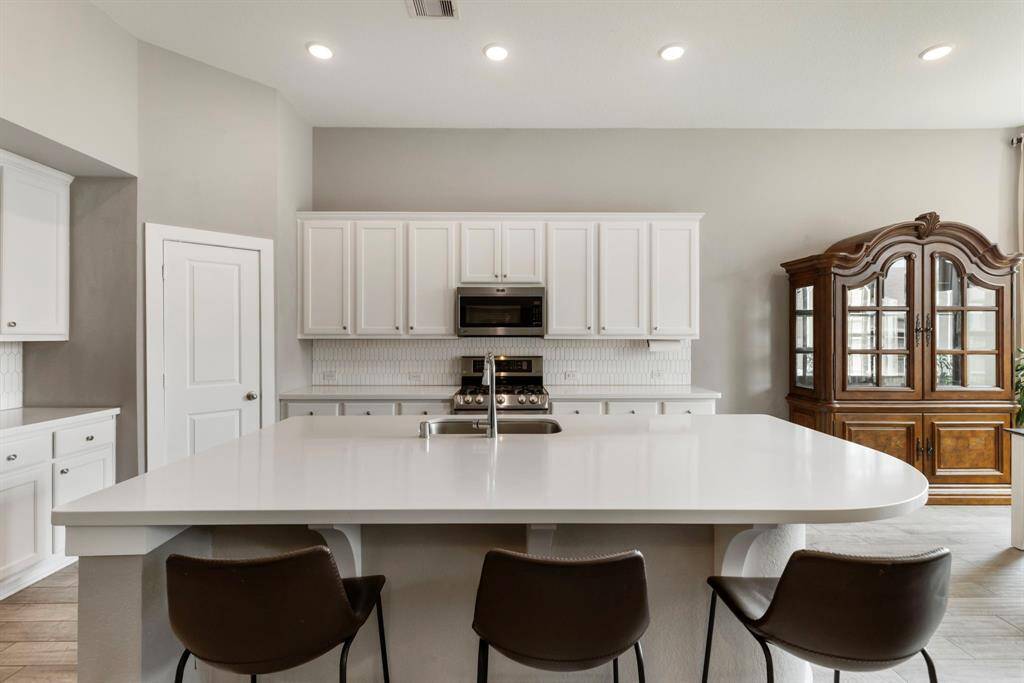 The stunning kitchen features an oversized island with Quartz countertops, undermounted stainless steel sink and space for additional seating.