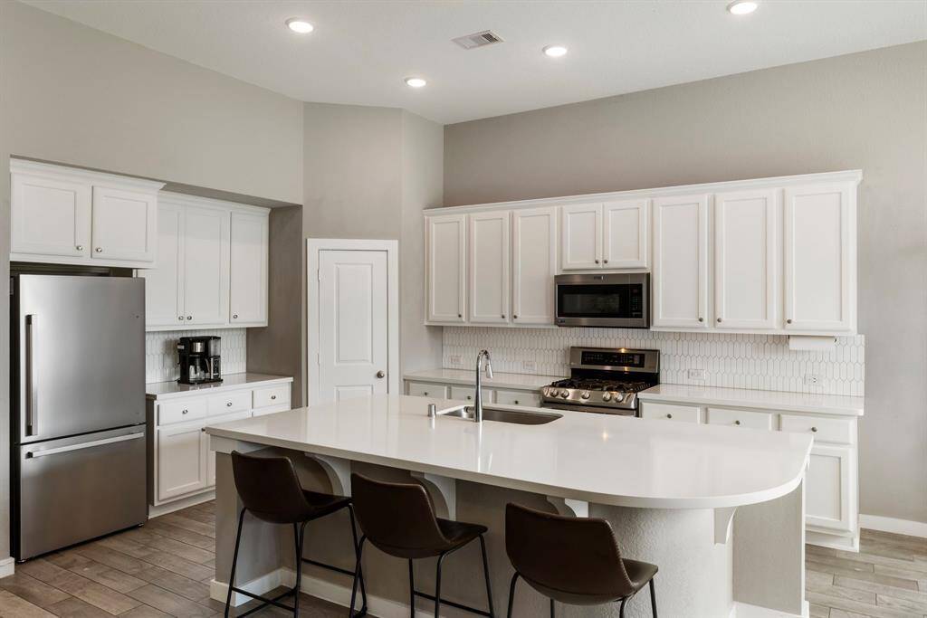 The bright white cabinetry is accented by a stylish tiled backsplash and stainless-steel Energy Star appliances - including a new Frigidaire dishwasher and Hisense refrigerator.