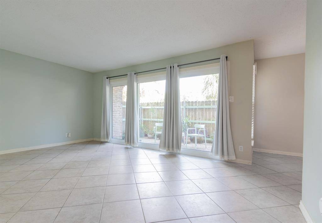 Living room with formal dining to the right. Patio in the background. Double-paned windows and sliding glass door.