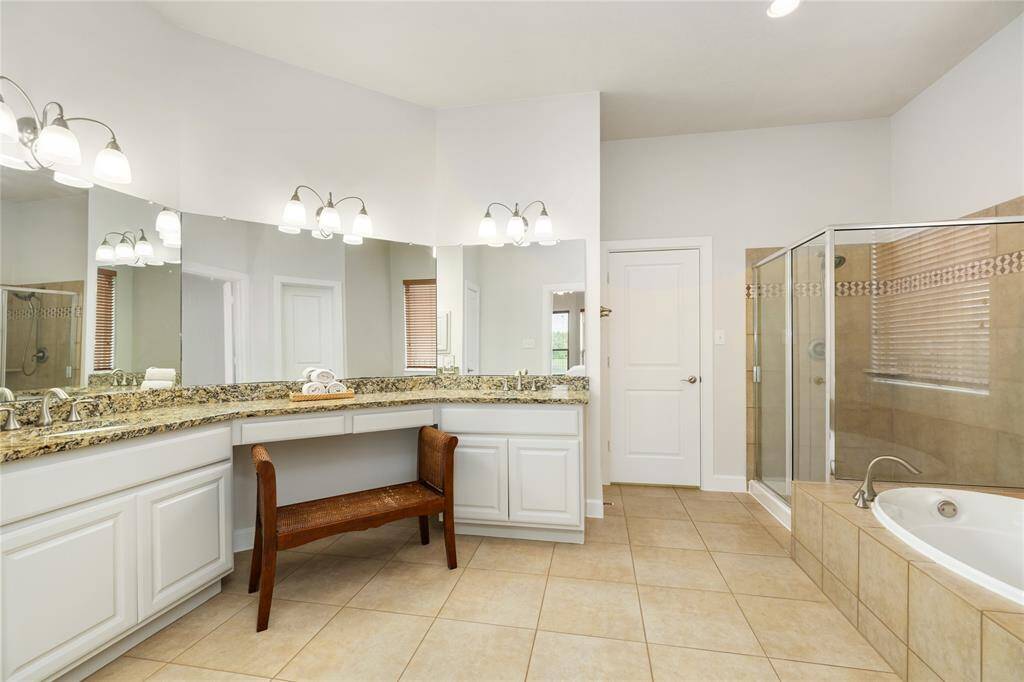 The luxurious primary en suite features dual vanities with granite countertops, a spacious makeup station, and a wall of mirrors for added light and function. Unwind in the large soaking tub or enjoy the separate walk-in shower. A generously sized walk-in closet completes this private retreat.