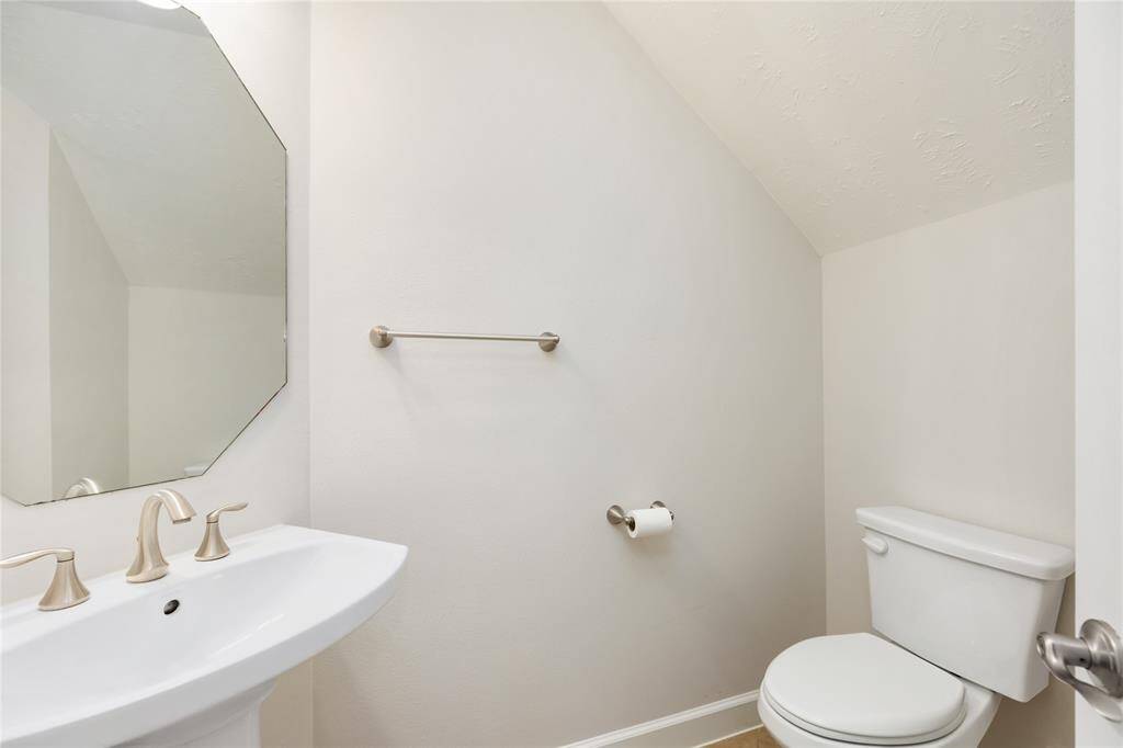This convenient downstairs half bath features a sleek pedestal sink, updated fixtures, and neutral tones—perfect for guests and everyday use.