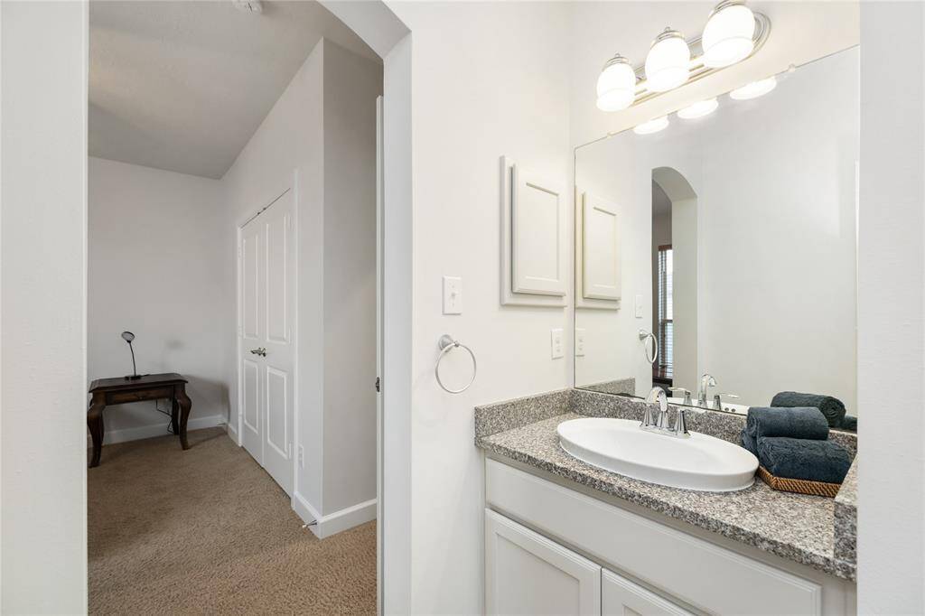 Two of the upstairs bedrooms conveniently share this well-appointed Jack-and-Jill bathroom, featuring a granite countertop, updated fixtures, and a spacious layout designed for functionality and privacy.