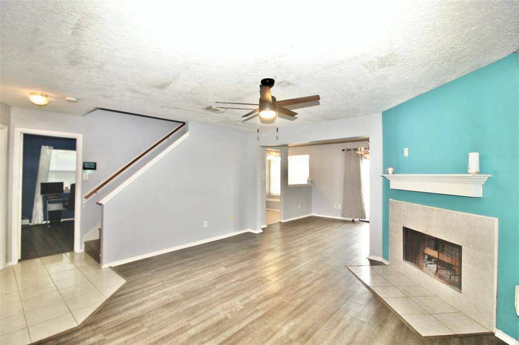 A view of the living room featuring a cozy chimney with primary bedroom on the first floor.