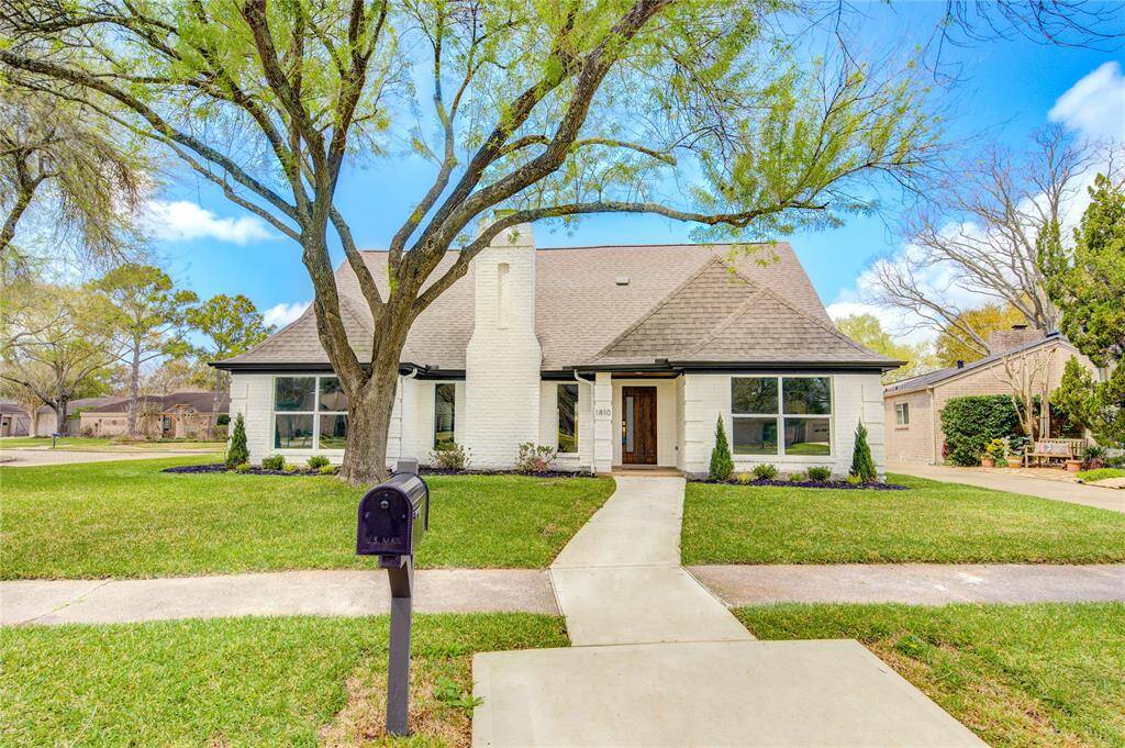 Nestled on a corner cul-de-sac lot, this contemporary home boasts a manicured front lawn shaded by mature trees. The inviting façade features a combination of brick and cement siding, leading to a welcoming front porch and a detached 3-car garage
