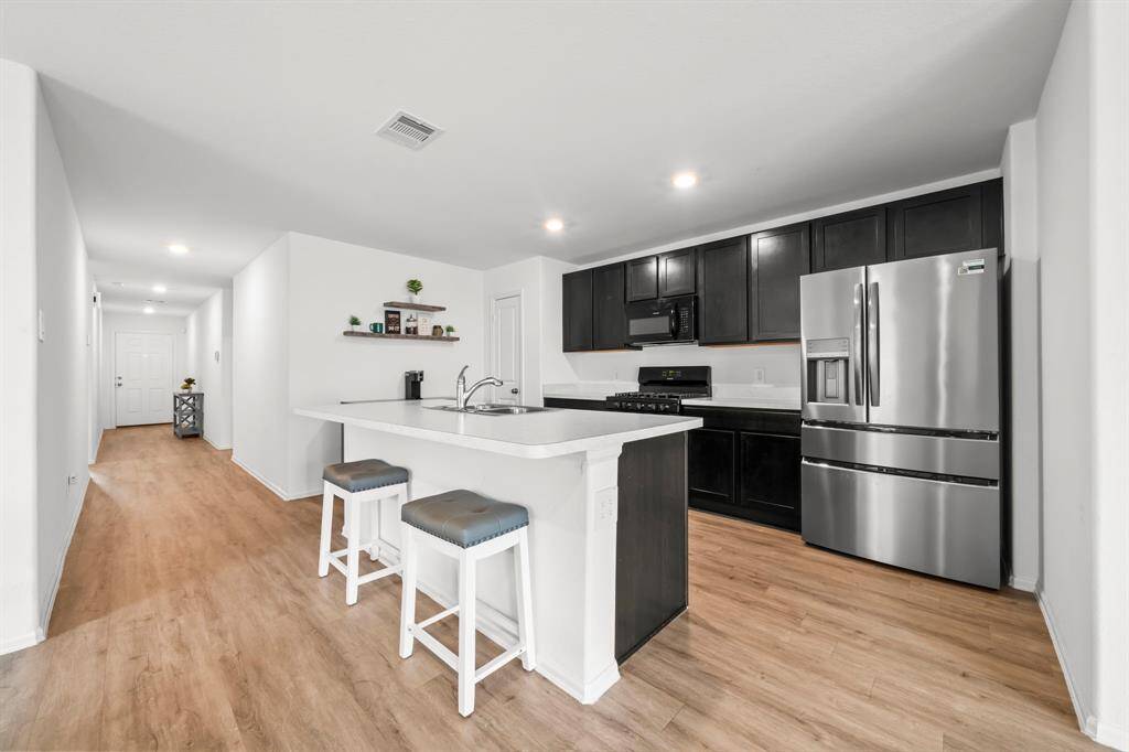 The kitchen is open to the living and dining area, creating a seamless and inviting flow for entertaining.A breakfast bar island adds extra seating and prep space, perfect for casual meals.