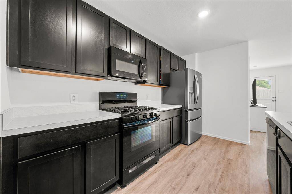 The kitchen features a gas stove, laminate countertops, and bold black cabinets for a modern, functional look.