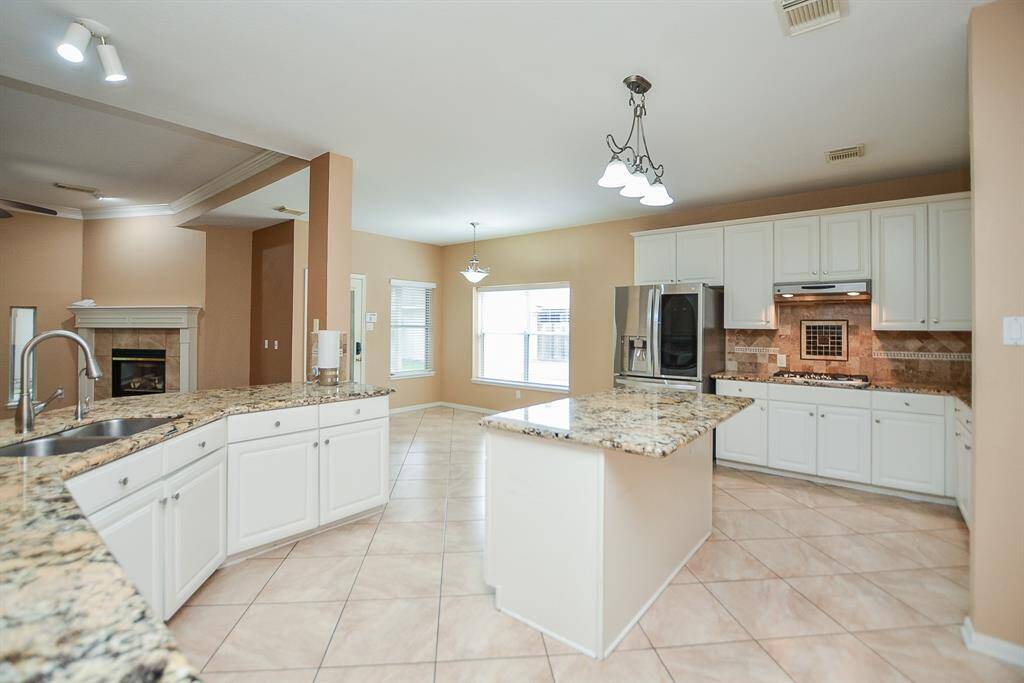 There's just something about a predominately white appointed kitchen that naturally invites family and friends. This amazing chef's kitchen hosts pale, earth toned tile floors, creamy granite counters and a dynamic copper toned tile backsplash.