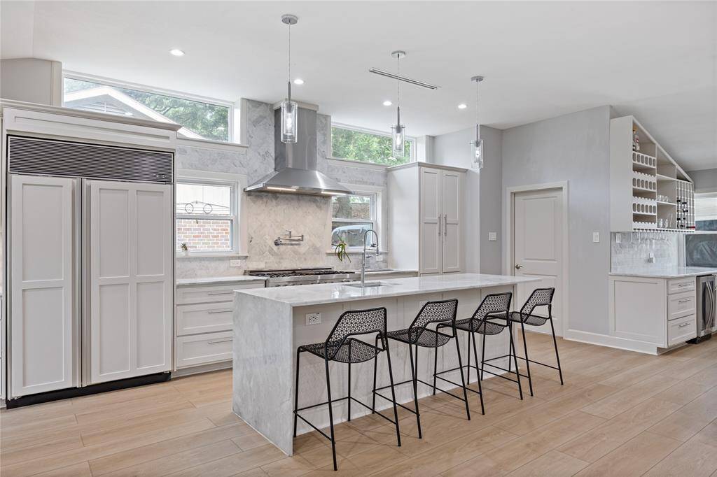 Luxury Chef’s Kitchen with Marble Island and Sub-Zero RefrigeratorWide-angle view of the custom kitchen featuring marble countertops, Sub-Zero 632 built-in fridge, pendant lighting, and bar seating—perfect for entertaining in style.