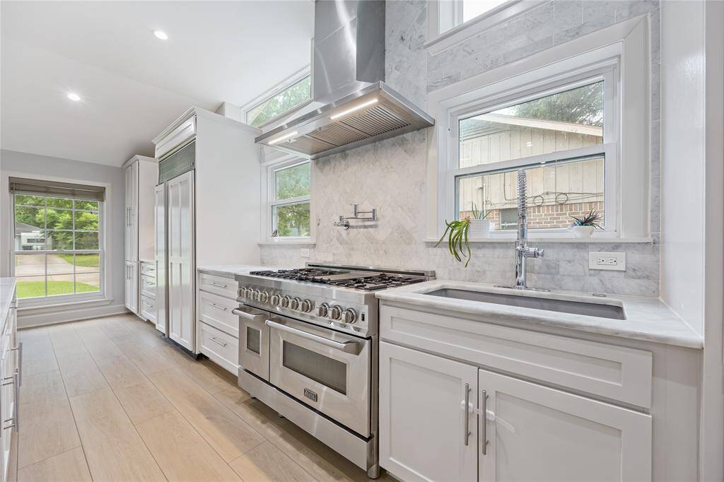 Professional ZLINE 48” Gas Range with Marble Backsplash and Dual WindowsThis chef-inspired cooking zone includes a pot filler, industrial vent hood, and elegant marble backsplash with natural light from two well-placed windows.