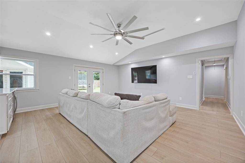 Vaulted Ceiling Living Room with Oversized Fan and Natural LightSpacious and bright with recessed lighting, luxury flooring, and direct backyard access via French doors—designed for relaxed living and effortless entertaining.