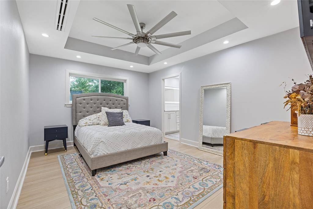 Primary Bedroom with Tray Ceiling and Oversized FanA serene retreat featuring a tray ceiling, recessed lighting, large window, and generous layout—designed for comfort and tranquility.