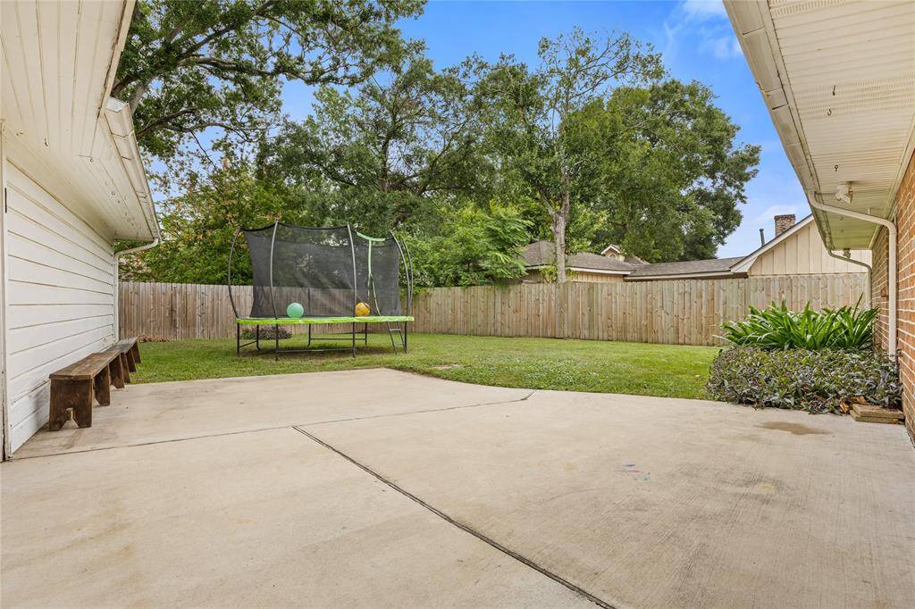 Covered Back Patio & Open YardSpacious concrete patio with covered breezeway ideal for outdoor entertaining. The fully fenced backyard offers privacy and plenty of room to play or garden beneath mature shade trees. A perfect space for gatherings or peaceful relaxation.