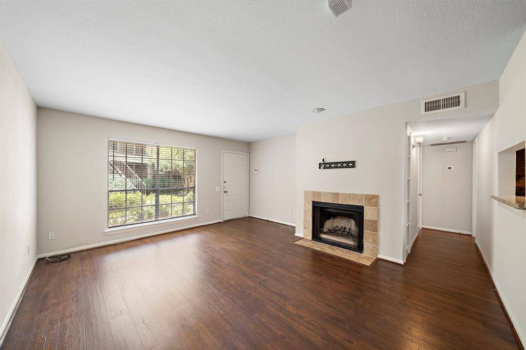 Large living room with wood burning fireplace and large window looking out to front patio.