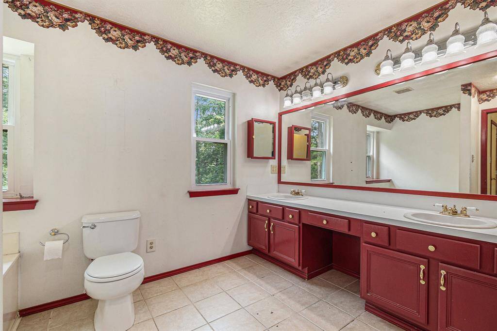 Primary bathroom has dual sinks, vanity seating, and a standing shower.