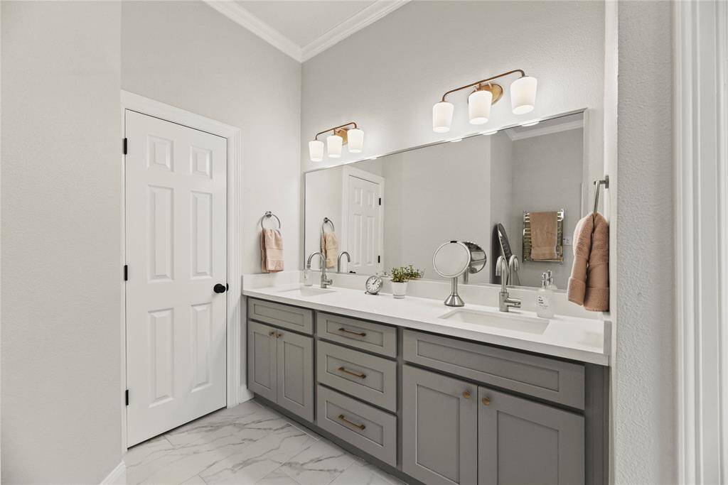 The spa like primary bath features dual sinks, updated lighting tile, cabinets and hardware with...