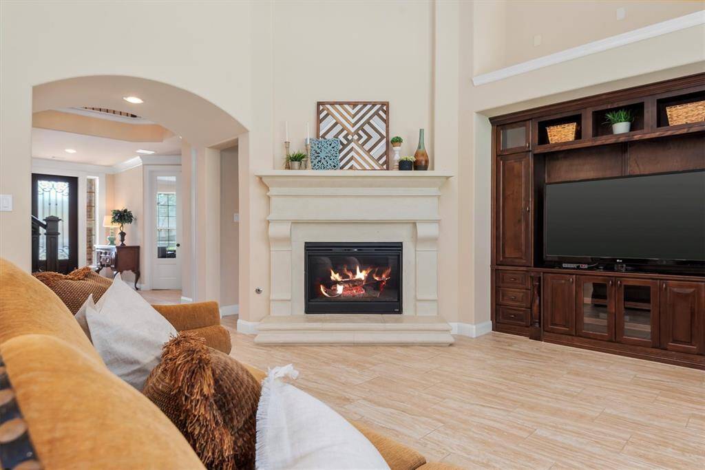 The living room makes a striking impression with its tall ceilings and abundance of natural light. Anchored by a grand, elegant mantle, the fireplace becomes a true focal point—perfect for cozy evenings or stylish gatherings. The open, airy feel of the space combines luxury and comfort, offering the perfect setting for everyday living and effortless entertaining.