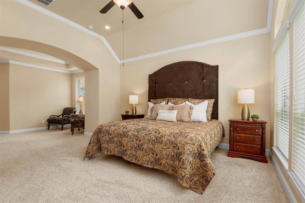 Retreat to a luxurious primary bedroom that offers both space and serenity. This oversized suite features an elegant layout with a dedicated seating area perfect for reading and relaxing.