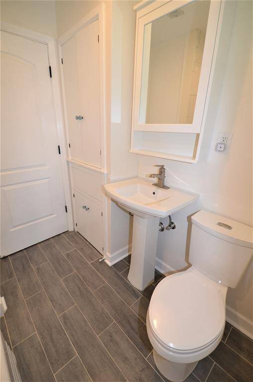 Full bathroom with wood plank porcelain tile floor and lot of storage.