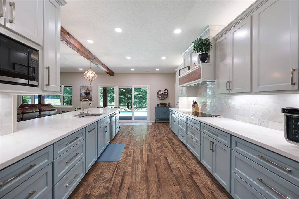 This stunning kitchen is both functional and beautiful, featuring an abundance of shaker-style cabinets in a soft two-tone palette—very light grey uppers and dusty blue lowers. The gleaming white quartz countertops provide ample prep space, while the deep workstation sink and stainless steel appliances complete the chef’s dream.