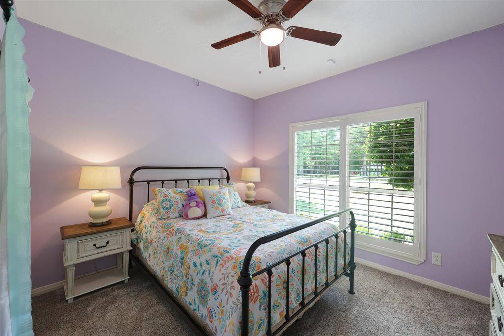 Bathed in natural light, this downstairs bedroom features a ceiling fan, plush carpeting (new) and large windows with plantation shutters that overlook the front yard.