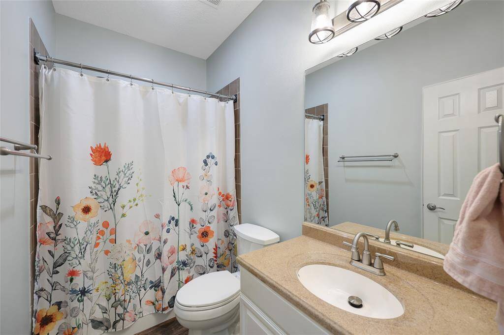 This full downstairs bathroom is designed with a soft, calming palette and features a single-sink vanity, brushed nickel fixtures, and a tub-shower combo. It's the perfect blend of style and practicality for guests or family use.