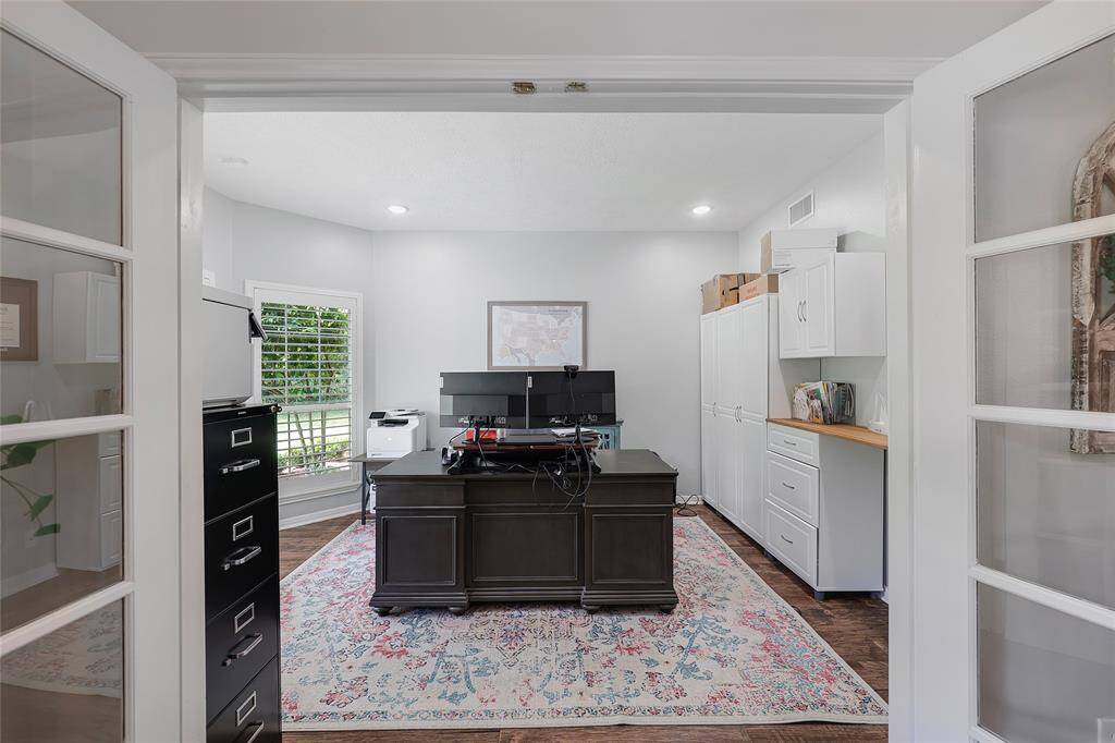 This dedicated home office offers a peaceful and productive setting with French doors, large windows, and ample built-in storage. The space comfortably accommodates a full executive desk and dual monitors, ideal for remote work or managing household affairs.