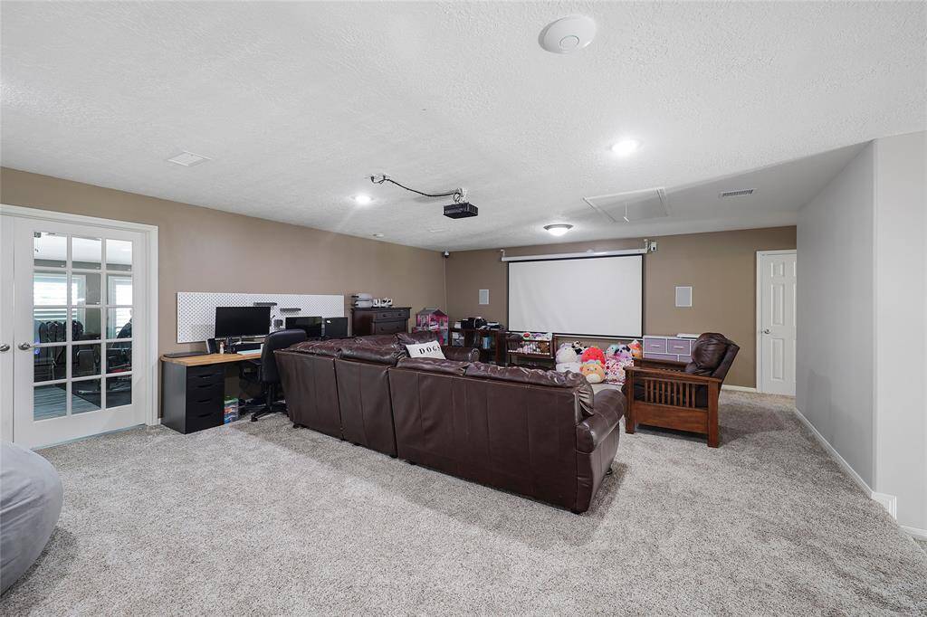 This spacious upstairs bonus room is perfect for movie nights, gaming, or casual hangouts. A wall-mounted projector and pull-down screen create a home theater experience. Off the game room is a bonus room with French doors which is currently used as a second study and a workout room. Also off the game room is a door that leads into the attic which is decked and has shelving for storage.