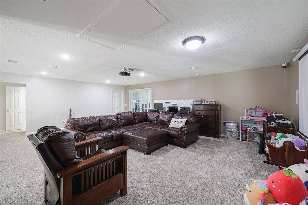 Another angle of the bonus room shows how multifunctional the space is, with zones for relaxing, working, and play. On the back wall on the right is a large storage closet with shelving.